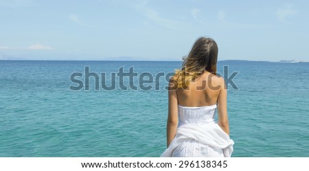 Young woman in a white dress looking at the horizon