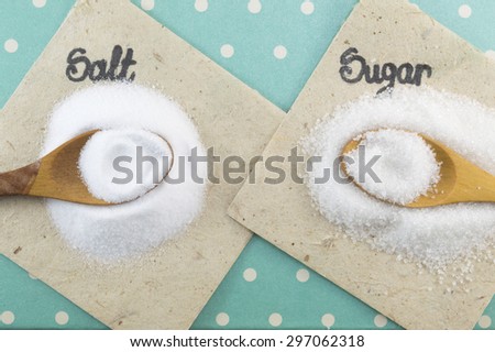 Spoons full of salt and sugar on a colorful dotted background