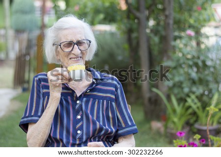 Smiling old grandma having cup of coffee outdoors