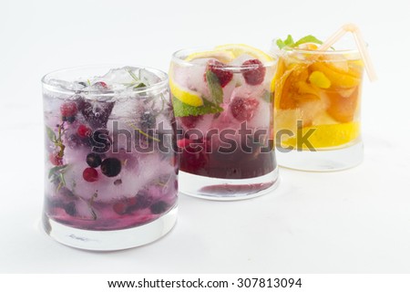 Three non alcoholic fruit cocktails with iced and sliced fruit on white background. Cold summer beverage