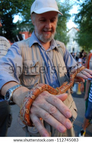 LJUBLJANA, SLOVENIA - AUGUST 30: Emonska Promenade, open air theater and creative tour, August 30, 2012, Ljubljana, SI. Zoo on visit with a friendly corn snake. Visitors touch it and get rid of fear.