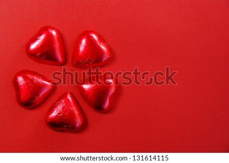Five red chocolate hearts on red background