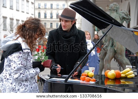 LJUBLJANA, SLOVENIA - MARCH 2: Davide Martello plays piano on Butcher's bridge in long winter in Ljubljana, SI, on March 2, 2013. In a break pianist gives autograph to the listener.