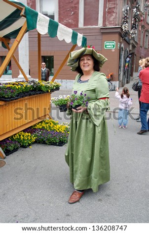 LJUBLJANA, SLOVENIA - APRIL 20: Unknown woman in fine oldfashioned clothes offers free flowers at campaign For Prettier Ljubljana (by Tourism) on Cobbler's bridge  in Ljubljana, SI, April 20, 2013.