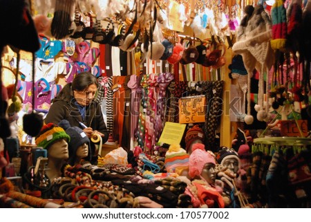 LJUBLJANA, SLOVENIA - DECEMBER 28, 2013: Vendor sells knitted caps, scarves, sweaters, ear muffs and other gifts for Christmas and New year\'s on  the street at pedestrian zone in the evening.
