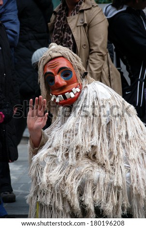 LJUBLJANA, SLOVENIA - MARCH 1, 2014: Traditional Slovene wooden facial mask with big teeth and costume, made of ropes (he is called Laufar, it means runner), at Dragon Carnival parade. Greeting