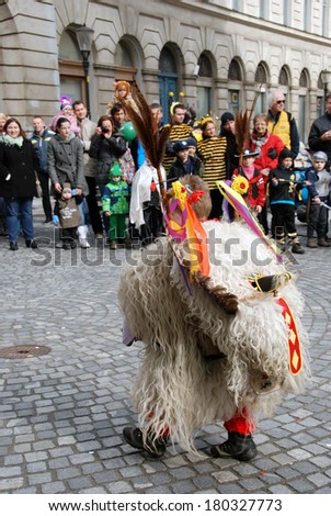 LJUBLJANA, SLOVENIA - MARCH 1, 2014: Young kurent takes down his heavy headgear of a traditional well known Slovene mask at Dragon Carnival parade. They banish away the winter and announce the spring.