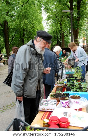 LJUBLJANA, SLOVENIA - MAY 17, 2014: Senior observes seedlings at Chelsea fringe festival - people switch seedlings, seeds or crop of their own. Various projects took place in towns throughout Europe.