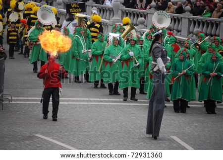 LJUBLJANA, SLOVENIA - MARCH 5: Brass band as green Ljubljana dragons with stilted policeman and a devil, spitting fire, and bees behind. Carnival parade in  Ljubljana, Slovenia,  March  5, 2011.