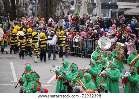 LJUBLJANA, SLOVENIA - MARCH 5: Brass band, dressed in green Ljubljana dragons, followed by little bees on a traditional carnival parade in  Ljubljana, Slovenia, Saturday,  March 5,  2011. Shrovetide.