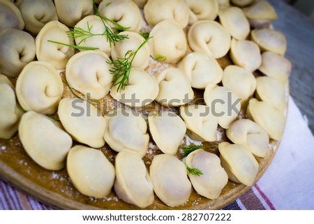 Traditional Russian pelmeni, raw meet dumplings on cooking desk.