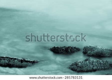 Sea waves and stones, long exposure used. Focus on the stones, evening time shoot. Great nature background. Relaxing and romantic seascape.