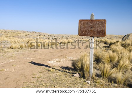 A rusty sign next to a gravel road in a arid region at Cordoba, Argentina