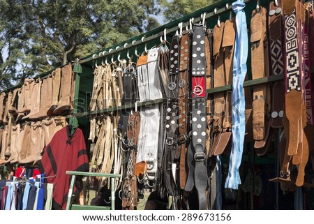 Traditional Argentinean leather gaucho belts, boots and cinchs hanging on for sale on a fair in Rosario city, Argentina
