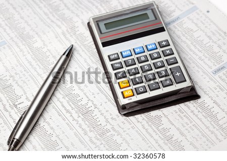 A calculator and pen on the stocks and shares page of a newspaper