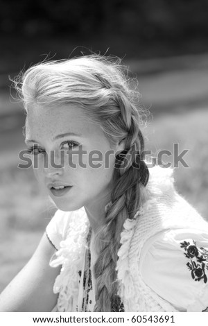 A black and white photograph of a beautiful blonde girl in country clothing and braids