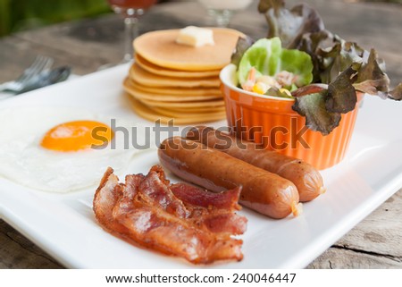 breakfast with fried eggs, bacon, sausages pancake and salad