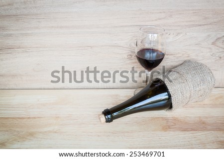 Bottle of red wine wrapped in a sack  on wood background