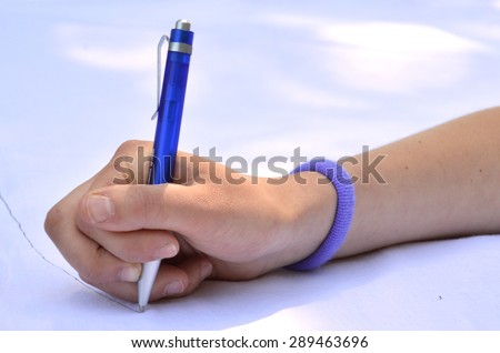 hand with pen writing on the white surface