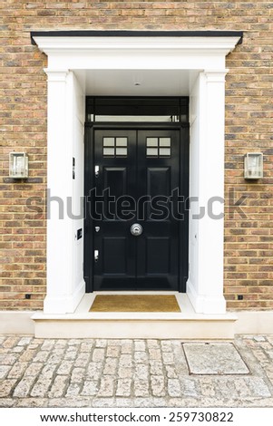 Black front door of a house with glass windows, London UK