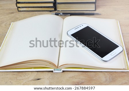 White smart phone on old book  and wooden desk.