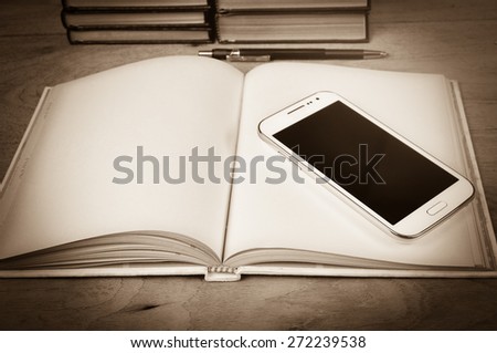 White smart phone on old book and wooden desk