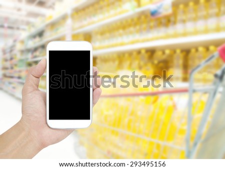 Hand holding mobile on Supermarket blur background , concept