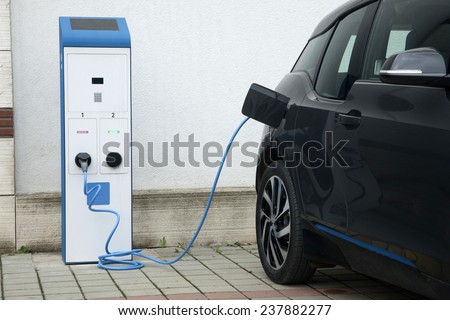 Power supply for electric car charging. Electric car charging station. Close up of the power supply plugged into an electric car being charged.