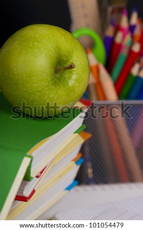 Green apple and pencil on pile of books