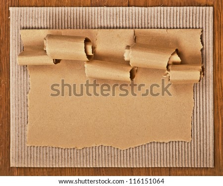 old textured cardboard sheet with torn edges wooden background