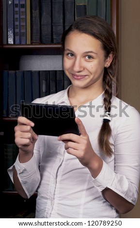 schoolgirl holding pile of books. Happy child with tablet computer