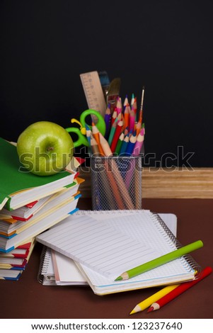 board, books, pencils, opened empty notebook lie on school desk