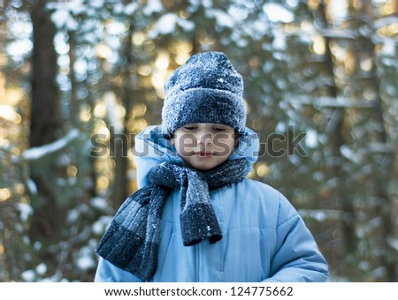 Adorable baby walking in snow winter forest touch wood branch on tree