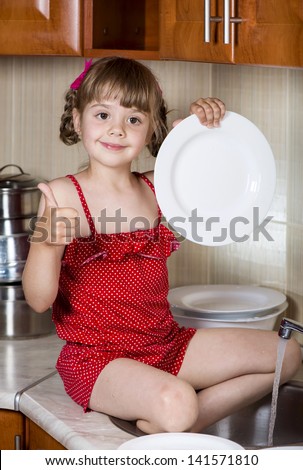 little girl in kitchen washes the dishes