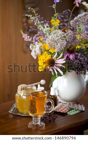 Still life from medicinal herbs, honey, herbal tea and medicines on a wooden background