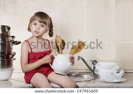 little girl in kitchen washes the dishes