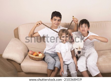 children and dog of breed the American bulldog sit on a sofa in the room