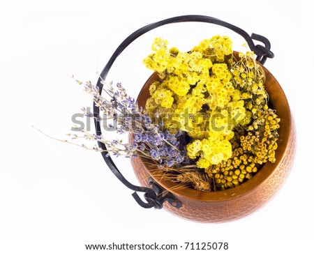 Dried medicinal grasses in a copper kettle on a white background