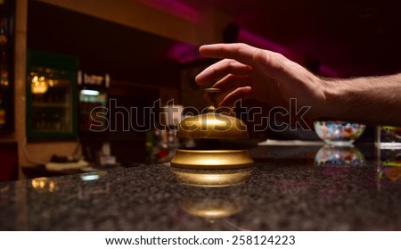 man hand ring the bell at the hotel front desk