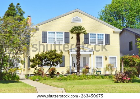 Yellow house with a palm tree on the lawn.