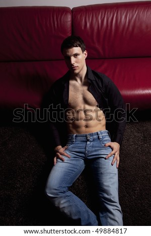 Pose of handsome sexy young man. Wearing black shirt, jeans, showing muscle body.