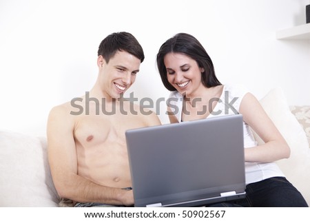 Nice beautiful couple with laptop, smiling, working and relaxing on the white sofa