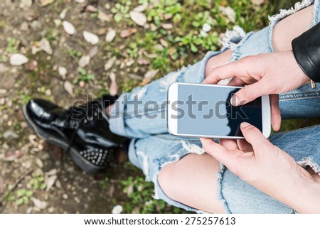 Girl with ripped jeans holding her smartphone