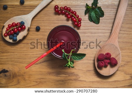 Currants, raspberries and blueberries on wooden spoons and a fresh juice with mint