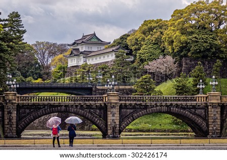 At the Imperial Palace. Two young ladies with umbrellas admire the striking Imperial Palace in Tokyo, Japan. Photograph shot on April 11, 2015