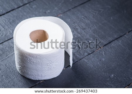 Toilet paper roll on the black wooden table