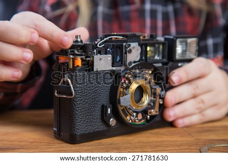Beautiful young girl repairing a broken vintage film camera
