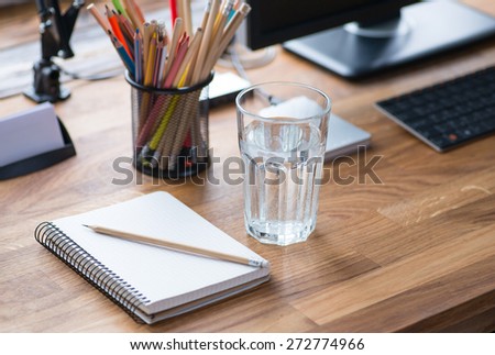 Light and cozy workplace with color pencils and glass of water