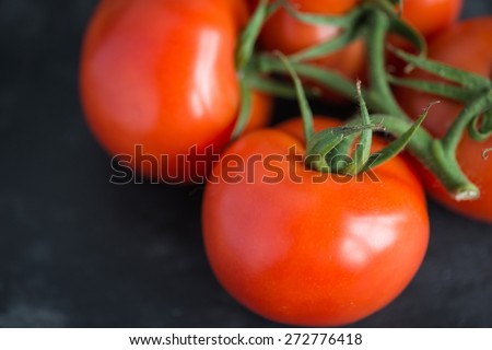 Fresh and tasty red tomatoes on a black stone serving board