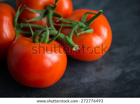 Fresh and tasty red tomatoes on a black stone serving board